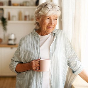 Senior woman looking out window while drinking tea