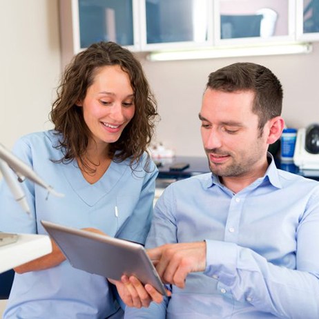 Patient and dental team member looking at tablet together