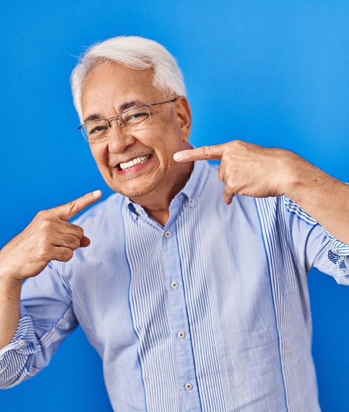 Confident senior man pointing at his teeth